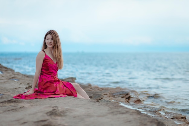 mujer joven, en, un, vestido rosa, sentado on the beach