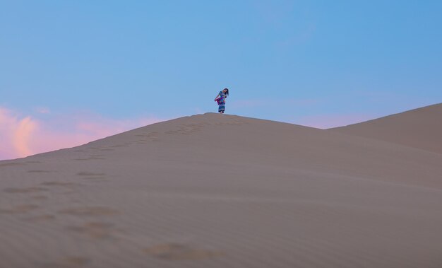 Mujer joven en un vestido de verano caminando sobre las dunas del desierto