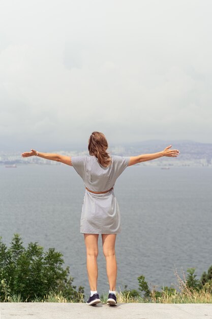 Mujer joven en vestido de verano mirando el paisaje urbano