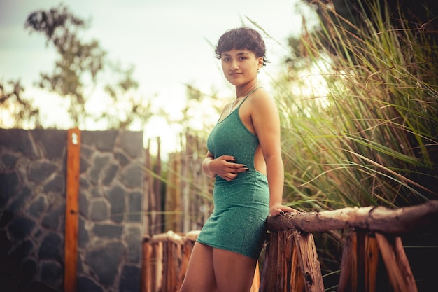 Mujer joven en vestido verde posando en la naturaleza