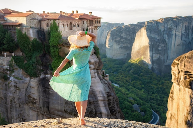 Mujer joven en vestido verde y un sombrero disfrutando de la naturaleza en las montañas cerca de los monasterios de Meteora Grecia Meteora increíbles formaciones rocosas de arenisca El área de Meteora está en la UNESCO