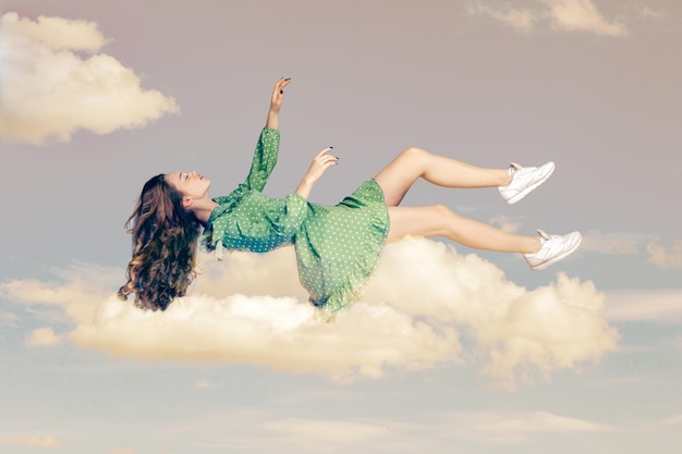 Mujer joven en vestido volando y durmiendo en el cielo