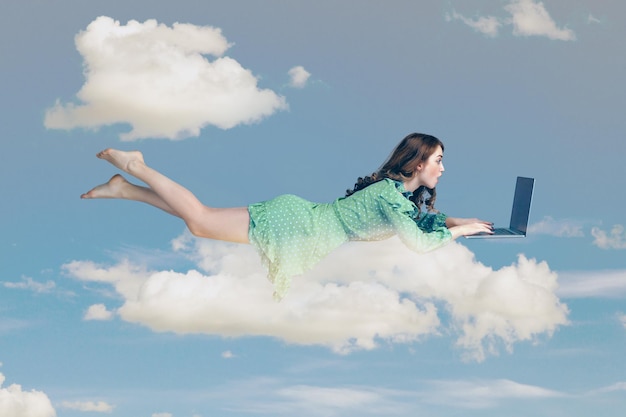 Mujer joven en vestido volando con laptop en el cielo