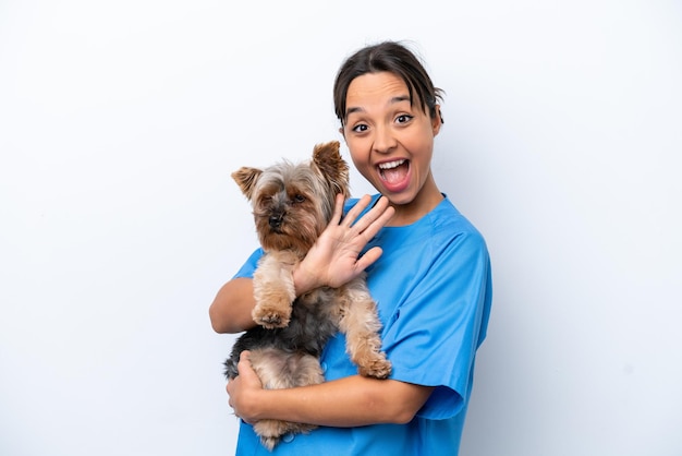 Mujer joven veterinaria con perro aislado sobre fondo blanco saludando con la mano con expresión feliz