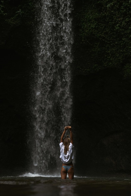 mujer joven viaja por la isla tomando fotos en una cascada
