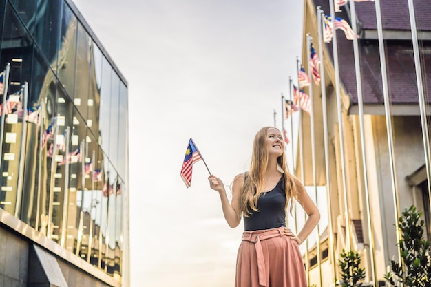 Mujer joven viaja en Malasia sostiene la bandera de Malasia