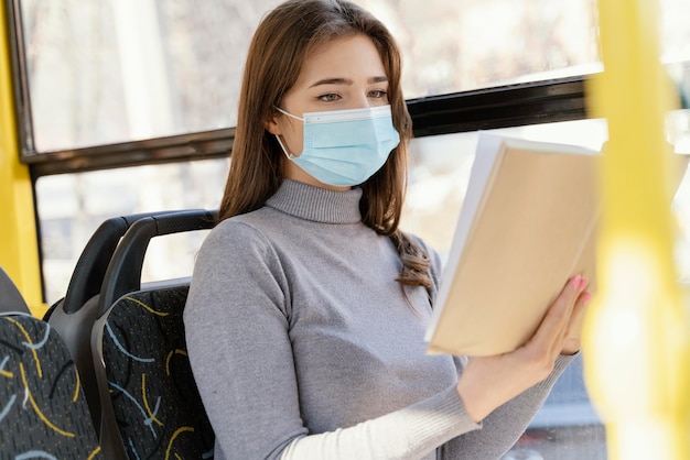 Mujer joven viajando en autobús urbano leyendo un libro