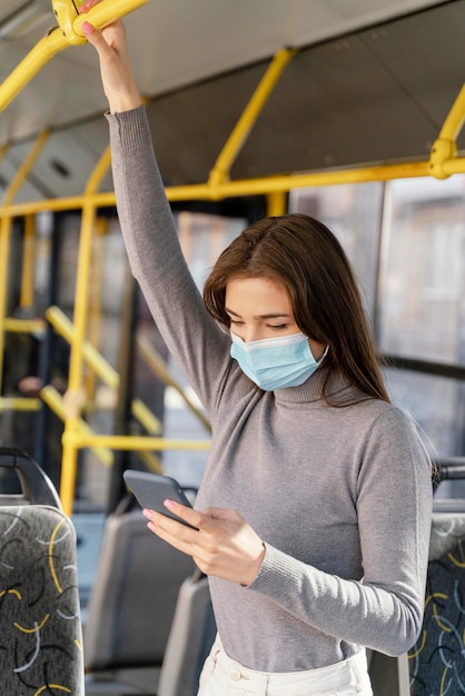 Foto mujer joven viajando en autobús urbano con smartphone