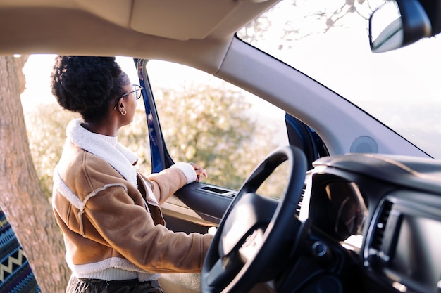 Mujer joven en un viaje de pie junto a una autocaravana