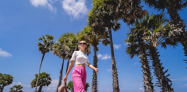 Mujer joven viajera en vacaciones de verano con hermosas palmeras y paisajes marinos