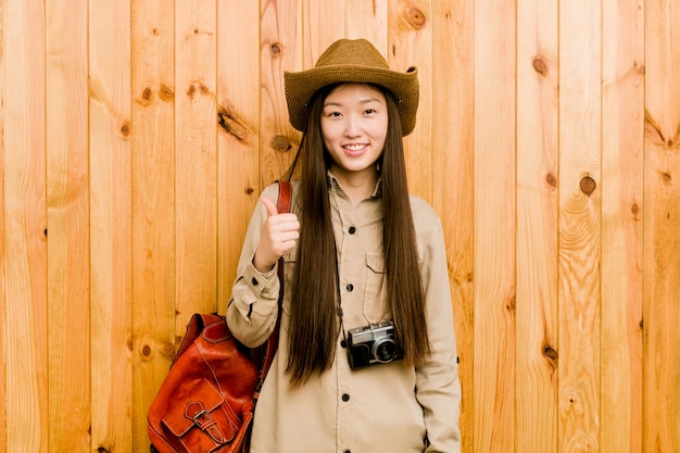 Mujer joven viajero chino sonriendo y levantando el pulgar hacia arriba