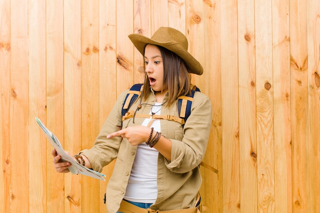 Mujer joven viajero con un mapa contra la pared de madera