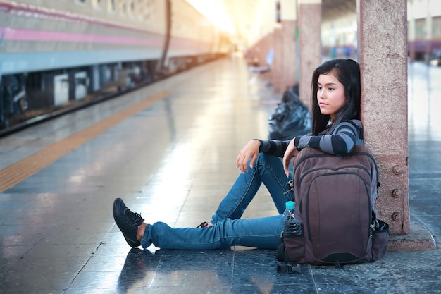 Mujer joven viajero sentado y esperando el tren