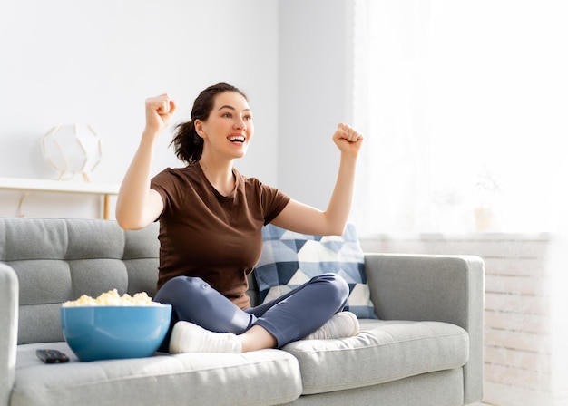 Mujer joven viendo películas de televisión con palomitas de maíz Chica pasando tiempo en casa