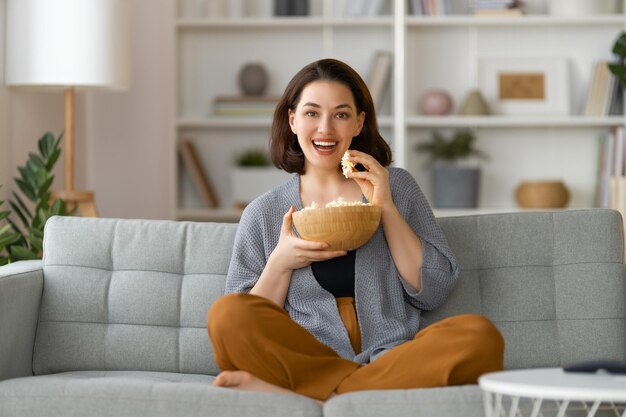 Mujer joven viendo películas de televisión con palomitas de maíz en la noche Chica pasando tiempo en casa