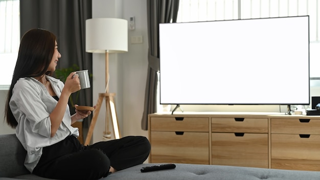 Mujer joven viendo la televisión en casa