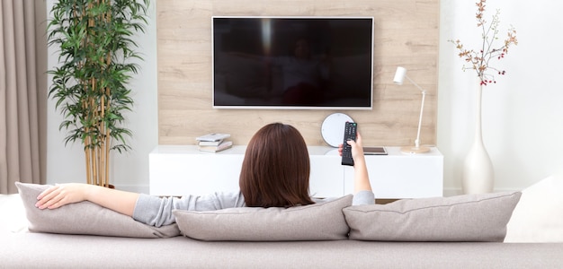 Mujer joven viendo la televisión en la habitación