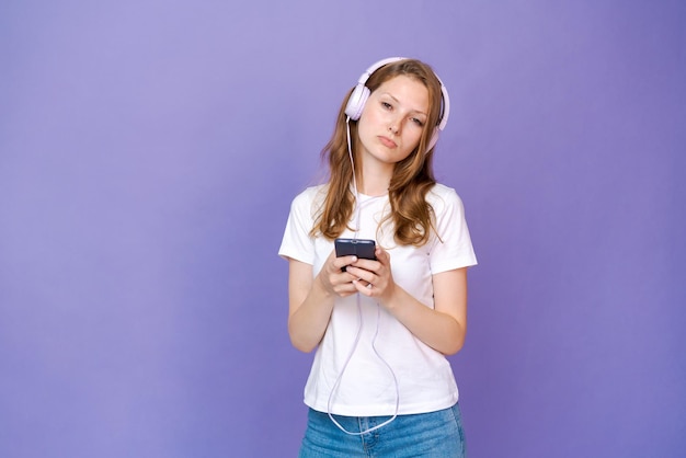 Mujer joven viendo videoclips en el teléfono en auriculares con cable en informal