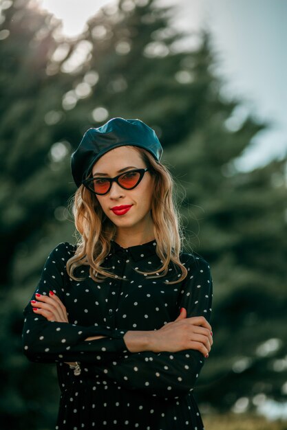 Mujer joven en vintage vestido de lunares negros posando afuera