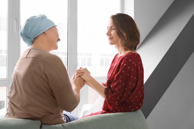 Foto mujer joven visitando a su madre con cáncer en el interior