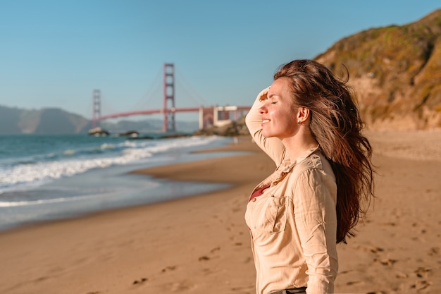 Mujer joven con vista sobre el puente Golden Gate en San Francisco.