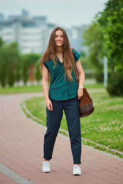 Una mujer joven viste ropa casual elegante disfrutando de su paseo por el parque