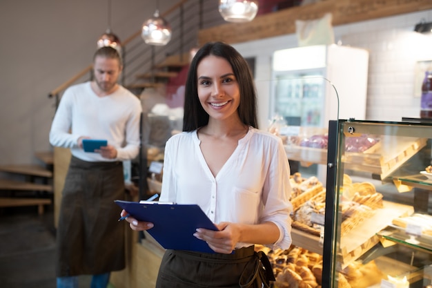 Foto mujer joven vistiendo un delantal en una panadería