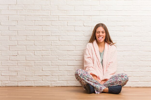 Mujer joven vistiendo pijama funnny y amable mostrando lengua