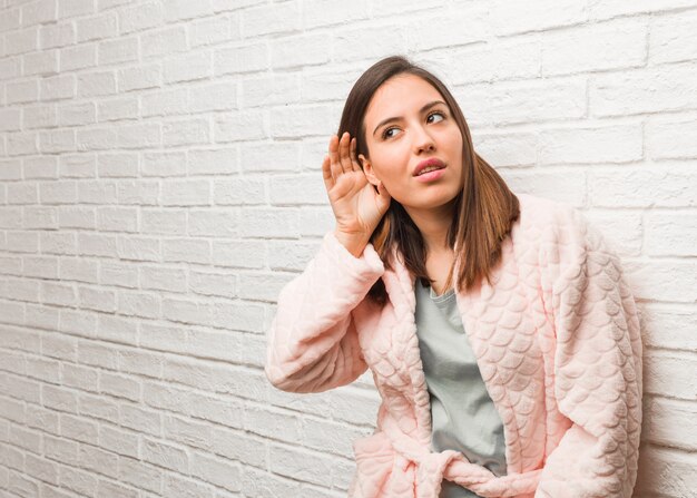 Mujer joven vistiendo pijama intenta escuchar un chisme