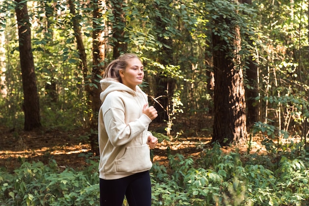 Mujer joven vistiendo sudadera deportiva corriendo en el parque concepto de bienestar y estilo de vida saludable