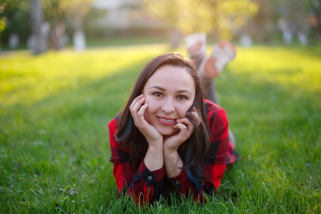 mujer joven yace en la hierba en verano y sonríe