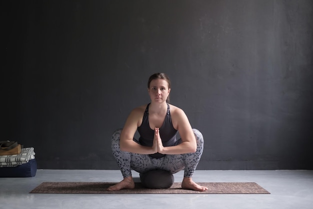 Mujer joven yogui practicando yoga sentada en Malasana