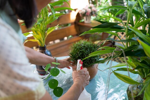 Foto mujer jubilada anciana regando plantas en el jardín durante su tiempo libre