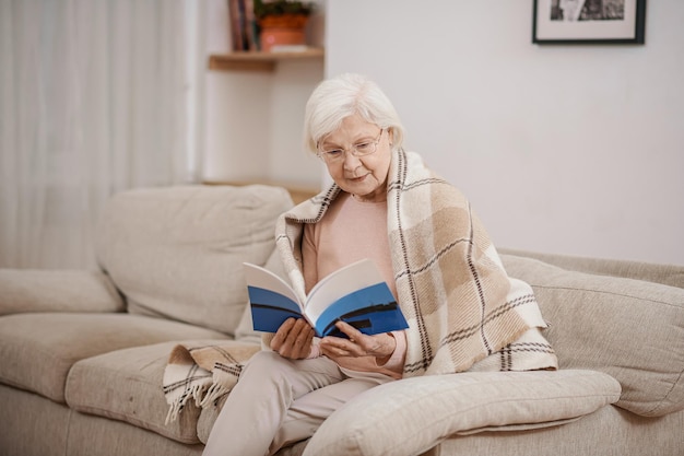 Mujer jubilada canosa tranquila concentrada en la lectura