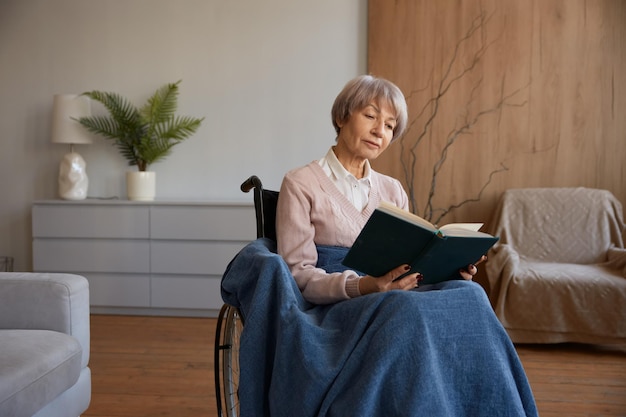 Mujer jubilada con discapacidad sentada en silla de ruedas leyendo un libro