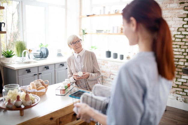 Mujer jubilada con gafas hablando con su cuidador