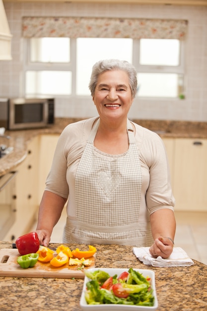 Mujer jubilada mirando a la cámara en la cocina