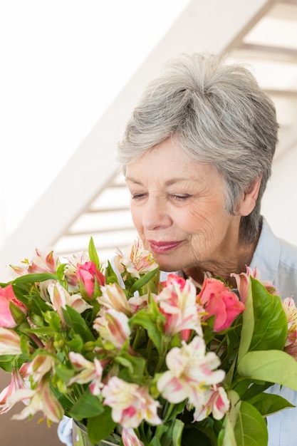 Foto mujer jubilada que huele su ramo de flores