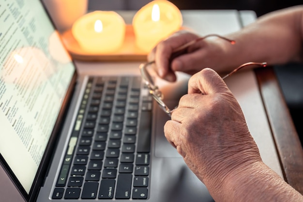 La mujer jubilada usa las manos de la computadora portátil de cerca