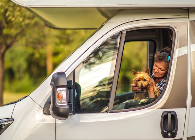 Mujer jubilada viajando con su perro silky terrier australiano dentro de una camioneta vacaciones en la carretera