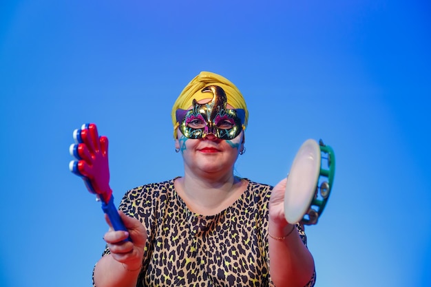 Foto una mujer judía con un tocado y una máscara de carnaval ordena cuándo hacer ruido en la sinagoga de purim durante la lectura del pergamino con sonajeros y tímpano foto horizontal