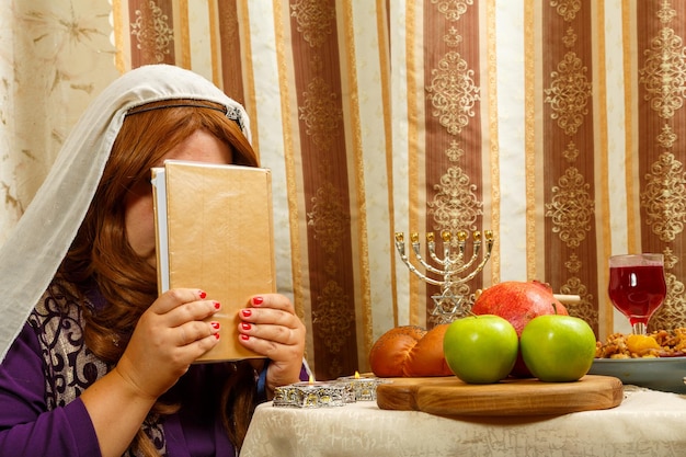 Una mujer judía con un velo que cae de su cabello sostiene un siddur en su rostro después de la oración festiva de Shabat y Rosh Hashaná.