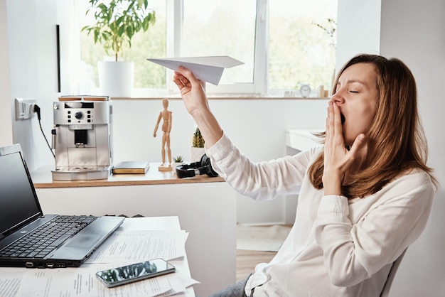 Foto mujer juega con papel plano en la oficina de casa procrastinar en el trabajo remoto