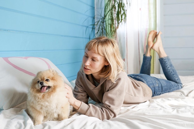 La mujer juega con el perro en la cama en el dormitorio