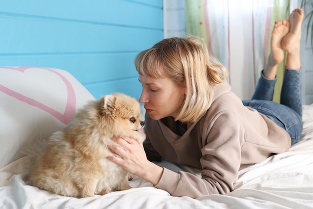 La mujer juega con el perro en la cama en el dormitorio