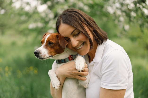 Mujer juega perro Jack Russell Terrier en la pradera. Mujer abrazando al perro Jack Russell Terrier en la naturaleza.