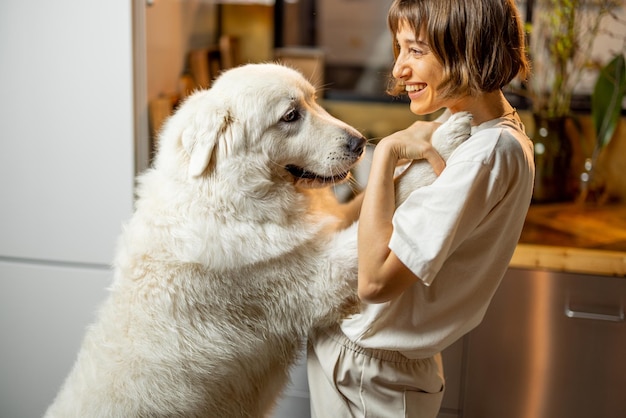 La mujer juega con su perro en la cocina de casa