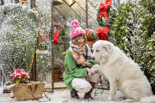 La mujer juega con su perro durante las vacaciones de invierno en el patio trasero