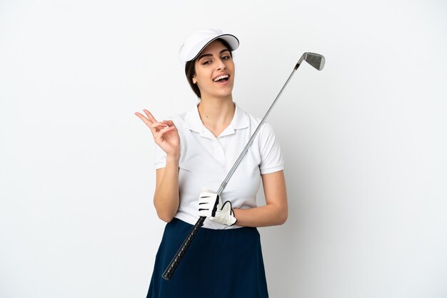 Mujer de jugador de golfista joven guapo aislado en la pared blanca sonriendo y mostrando el signo de la victoria