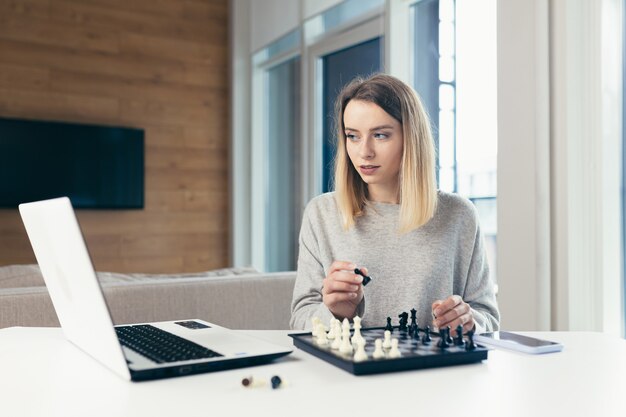 mujer jugando al ajedrez en línea usa laptop